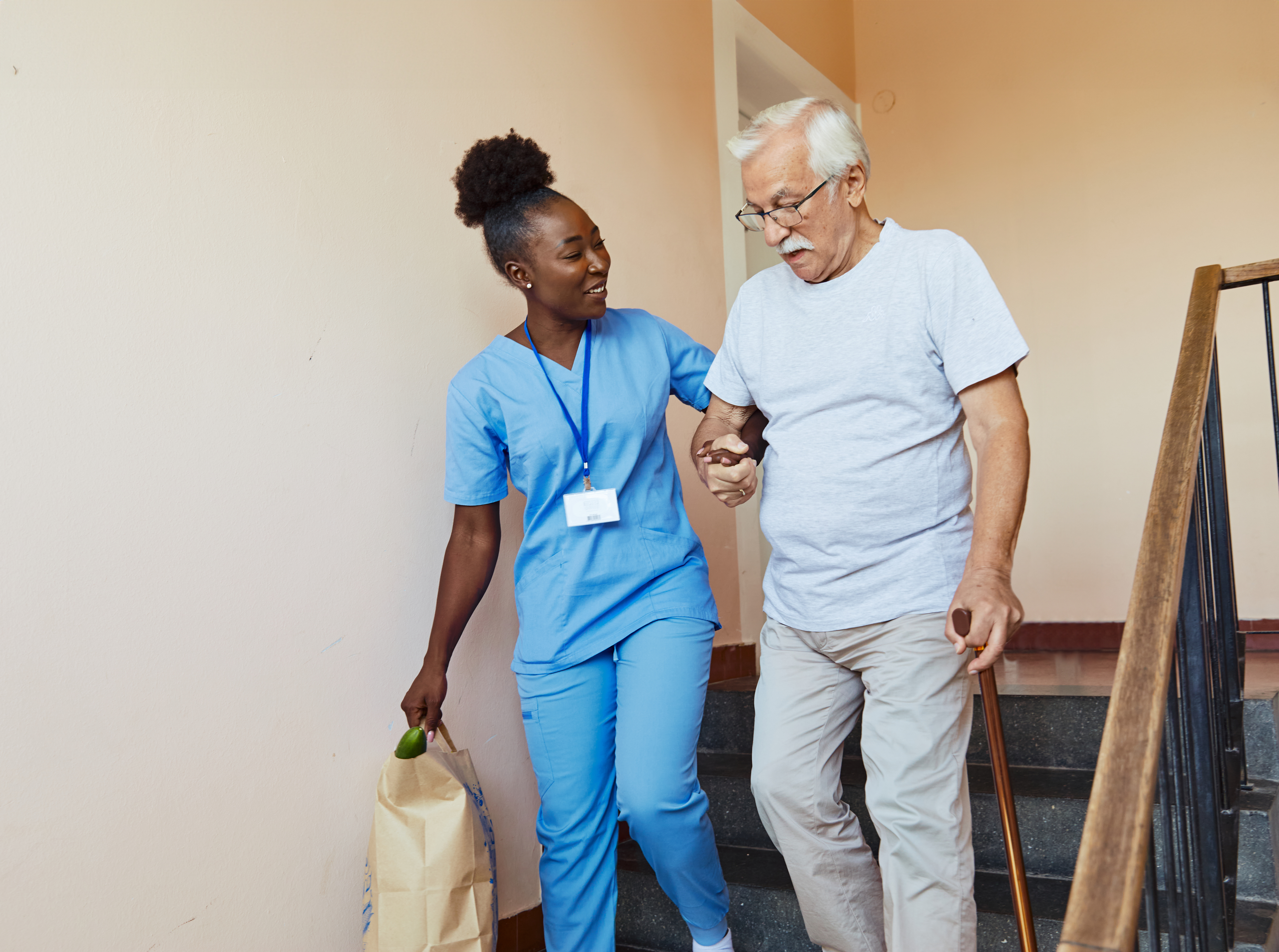 Doctor or nurse caregiver helping disabled senior man walking down the stairs at home or nursing home