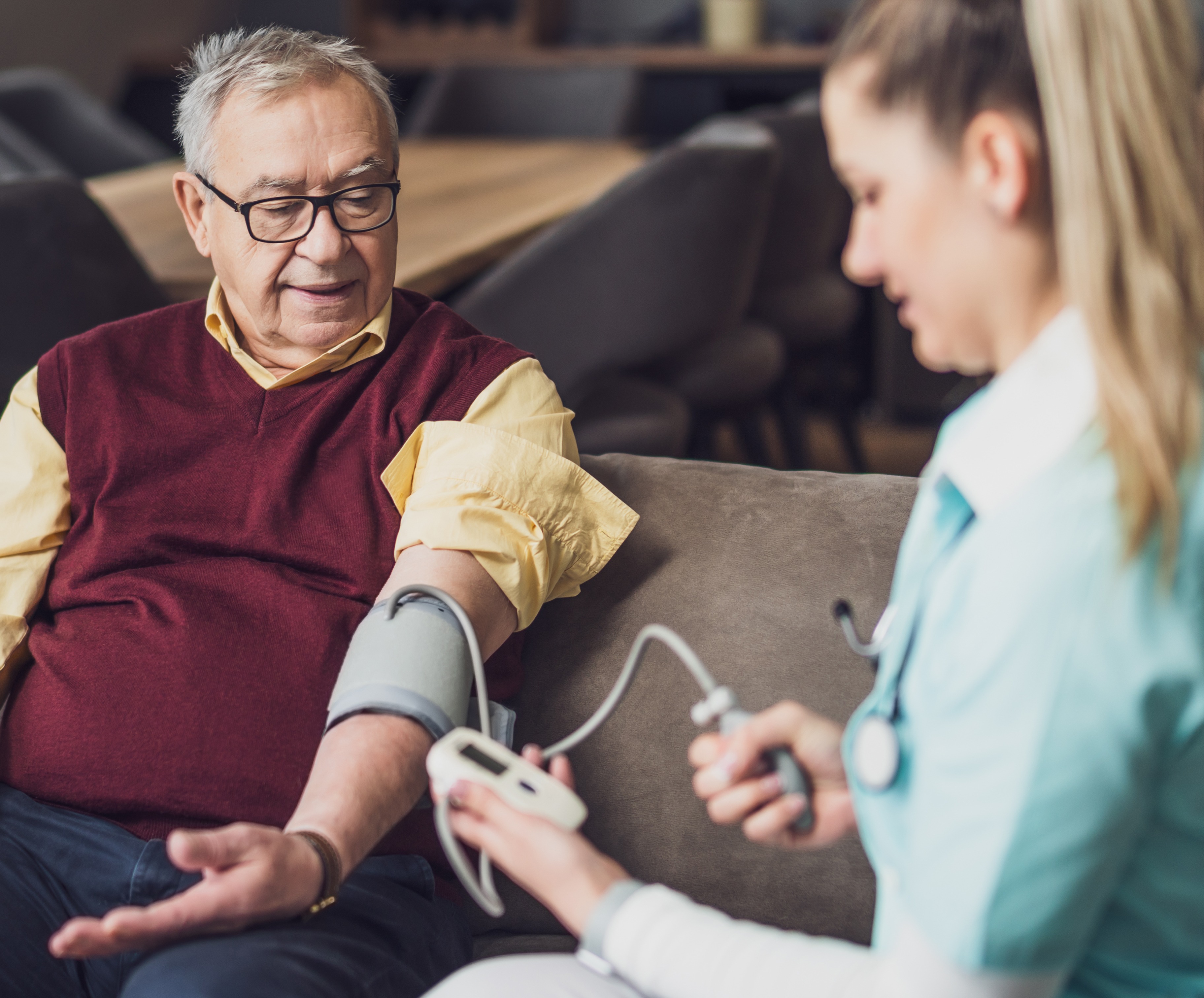 Homecare nursing service and elderly people cardiology healthcare. Close up of young hispanic female doctor nurse check mature caucasian man patient heartbeat using stethoscope during visit