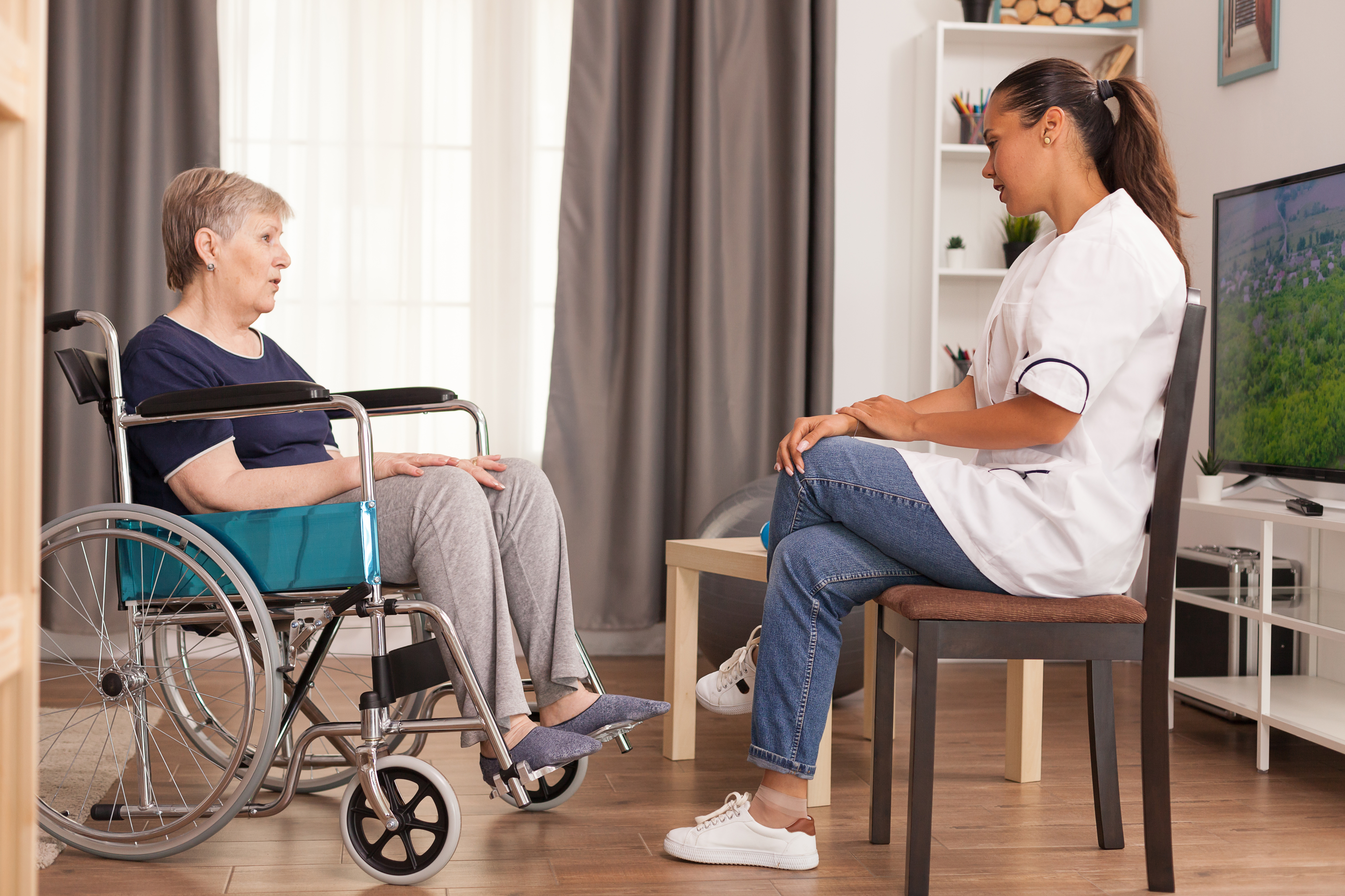 In-home caregiver talking with senior in a wheel chair